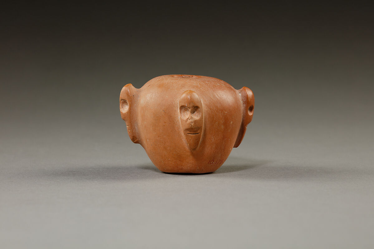 Piriform macehead with male faces, Limestone (pink), organic material