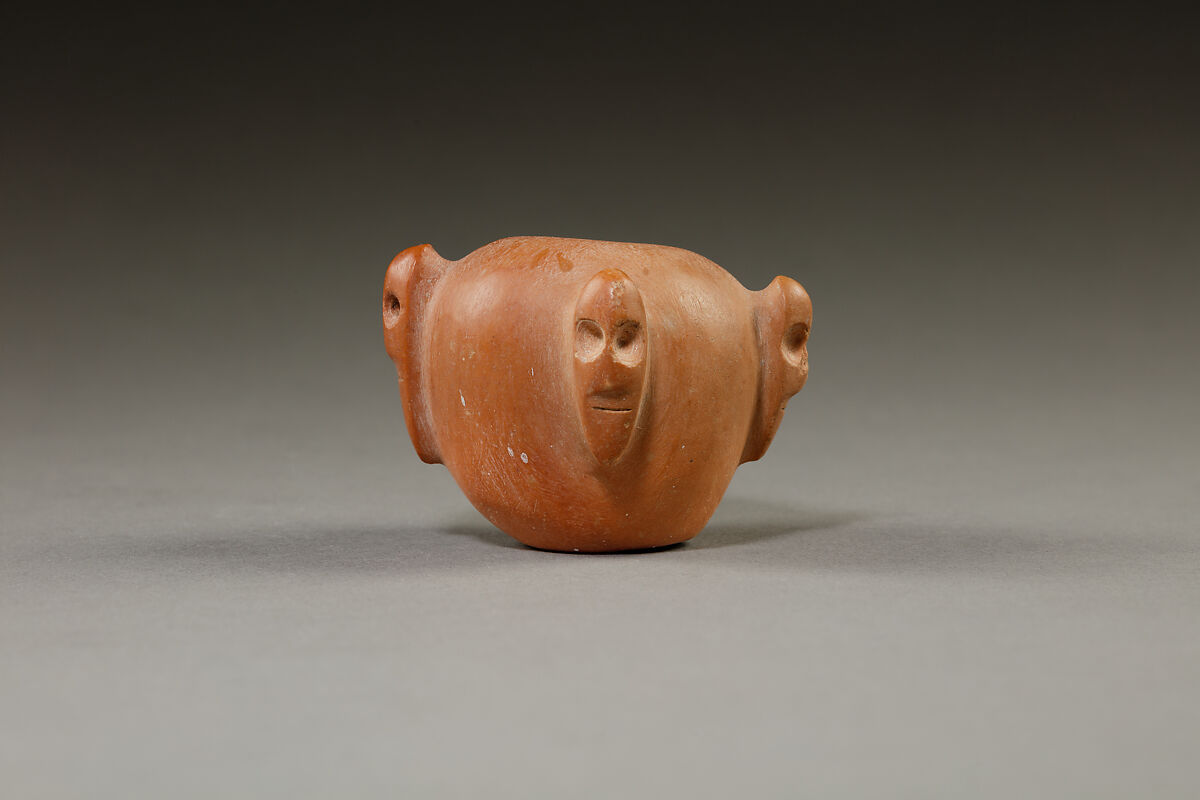 Piriform macehead with male faces, Limestone (pink), organic material