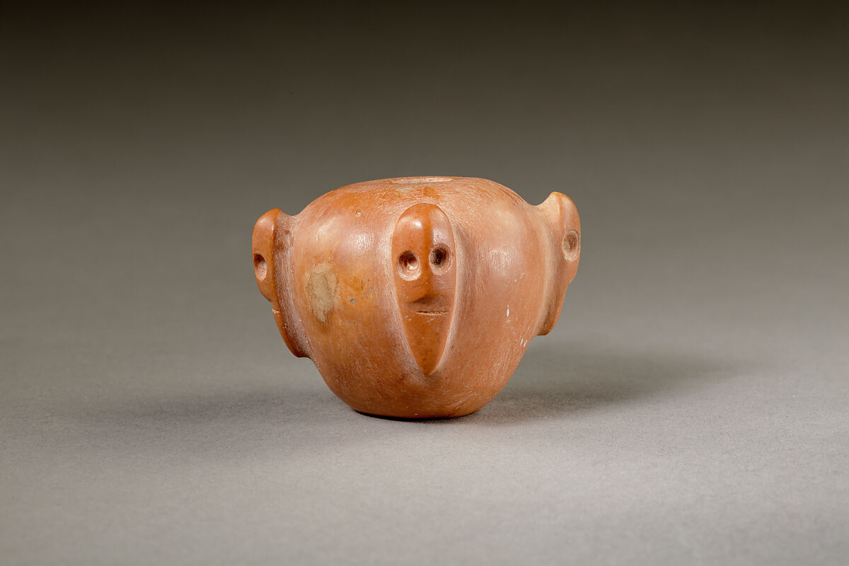 Piriform macehead with male faces, Limestone (pink), organic material