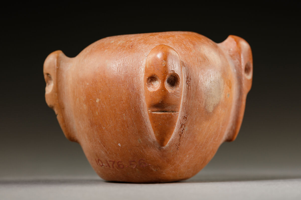 Piriform macehead with male faces, Limestone (pink), organic material