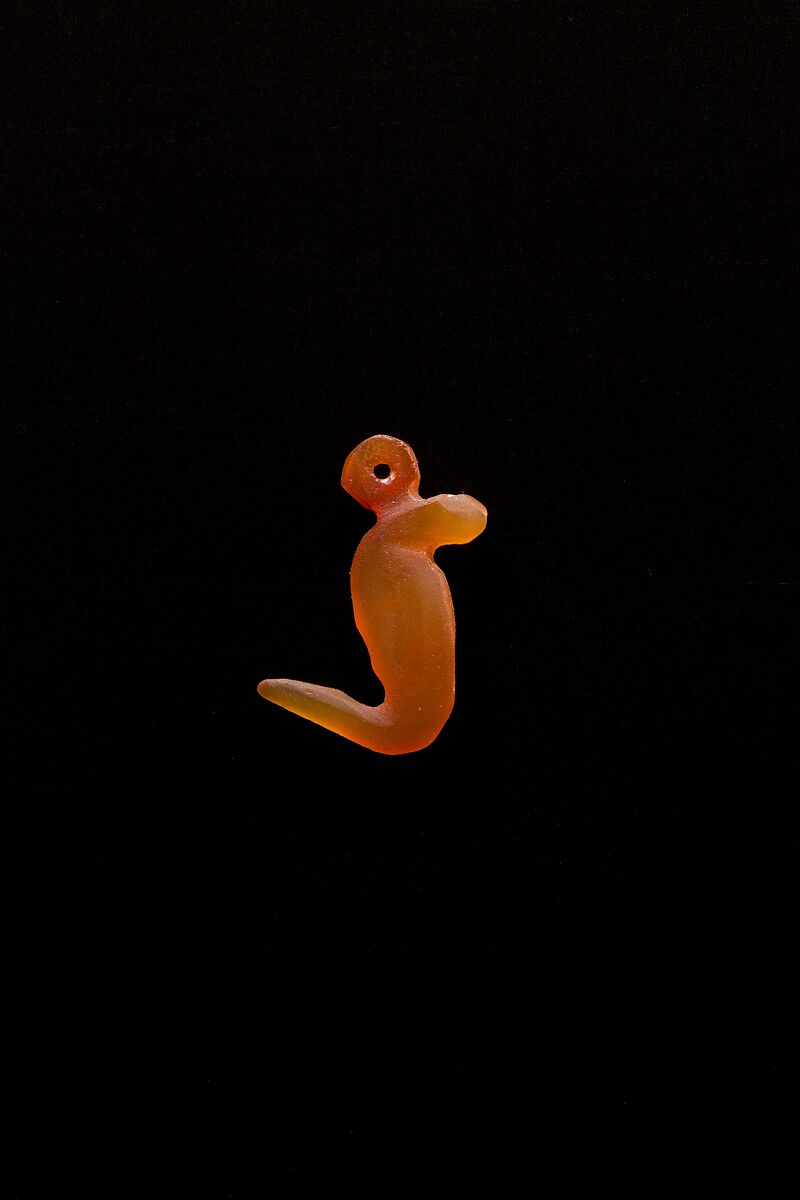 10 Amulets: 1 wedjat, 1 scarab, 3 djed pillars, 1 incised plaque, 1 uraeus, 2 wadj signs, and 1 cylindrical bead, Lapis lazuli, stone, carnelian, glass