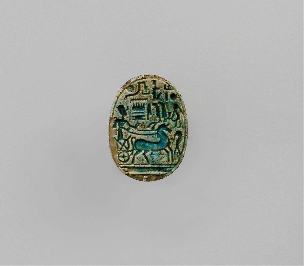 Scarab Inscribed With the Prenomen of Ramesses II and depicting the king in his chariot trampling an enemy, Steatite, blue glaze 