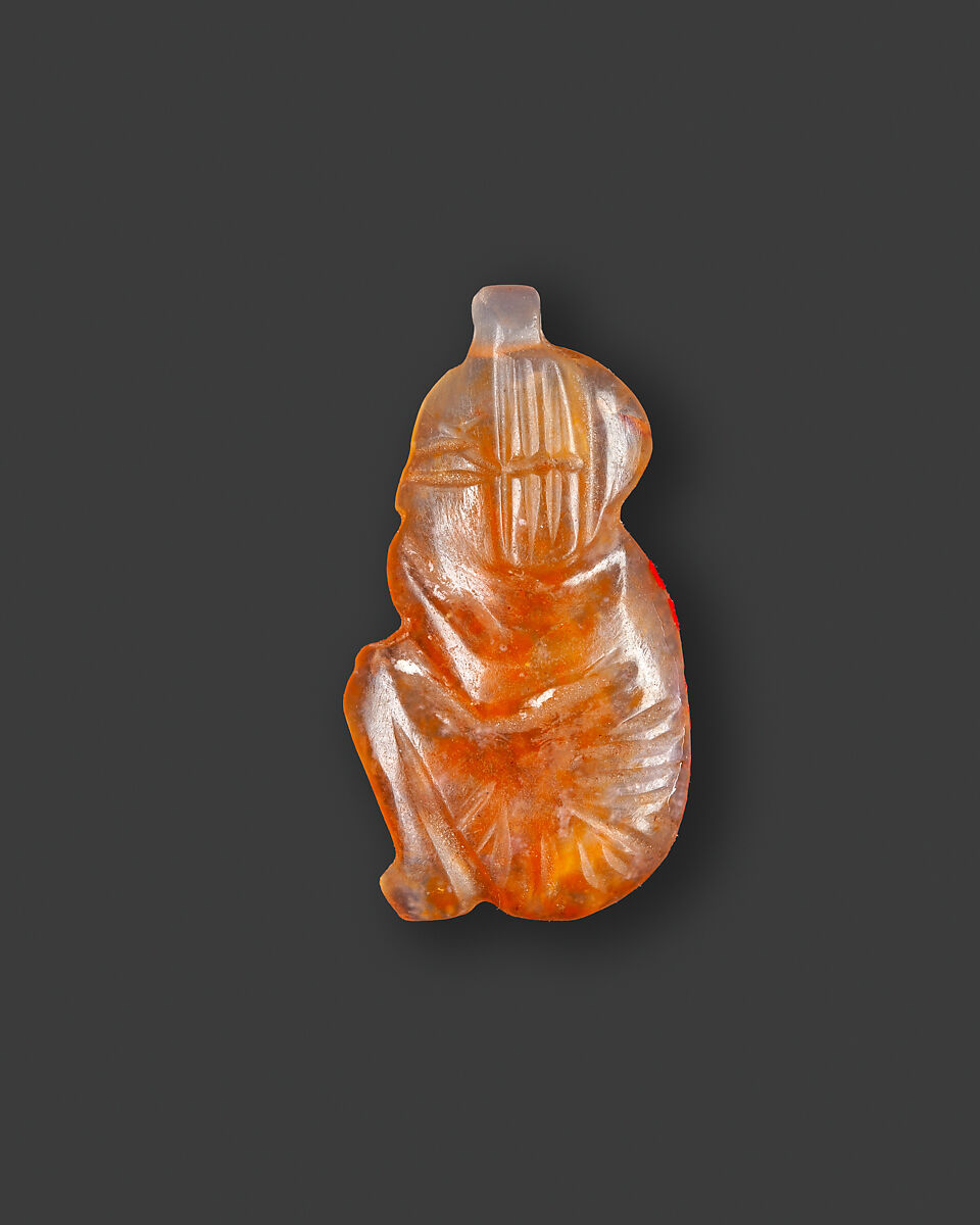 Amulet of a squatting royal male child with the name Usermaatre Ramesses on the underside, Carnelian 