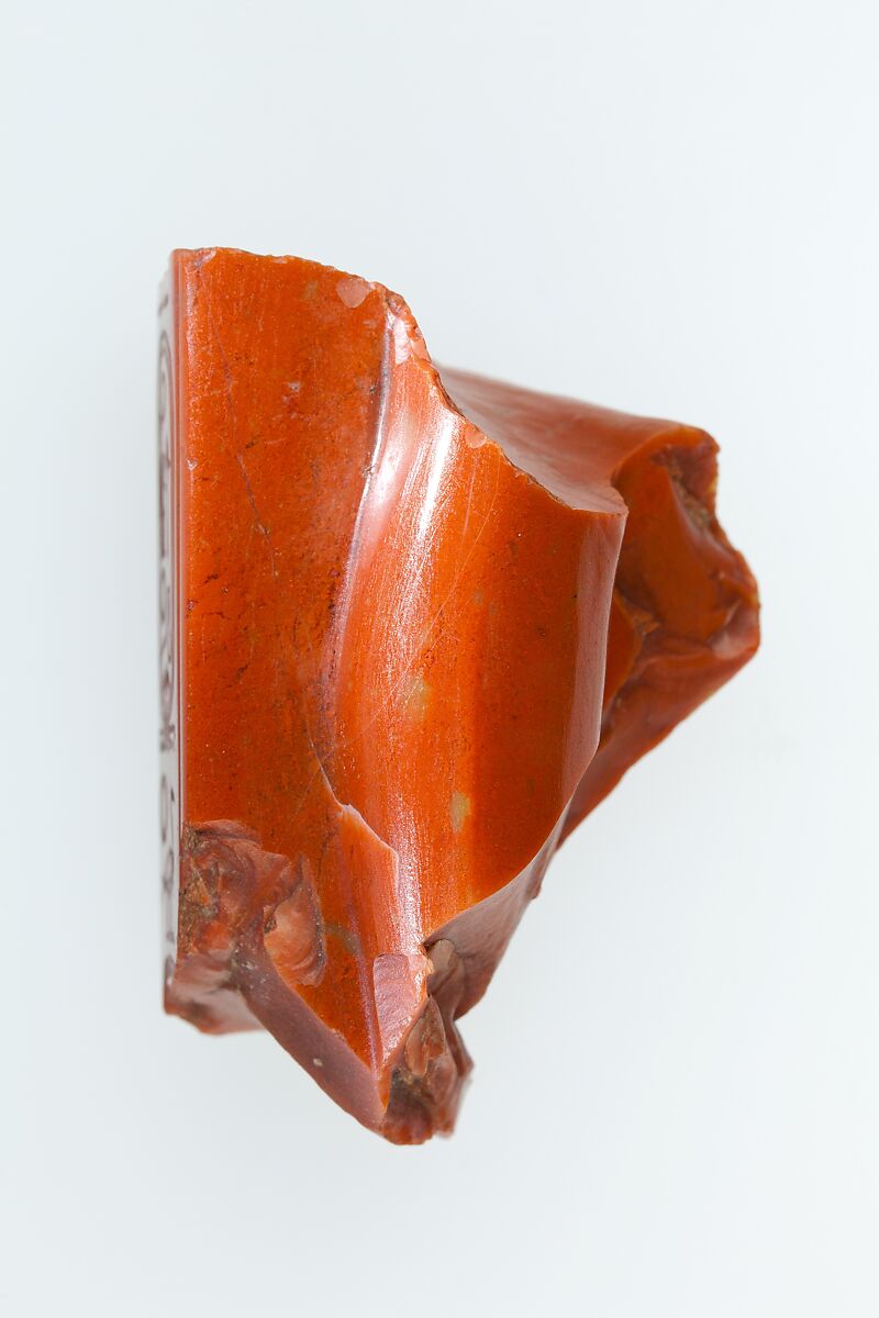 Statue fragment from a standing figure whose back pillar has cartouche of Ramesses II, and the figure of queen Nefertari incised on side, Red Jasper