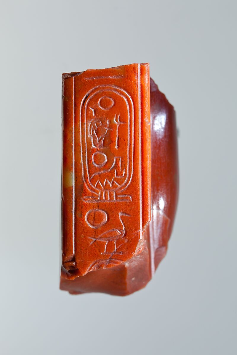 Statue fragment from a standing figure whose back pillar has cartouche of Ramesses II, and the figure of queen Nefertari incised on side, Red Jasper