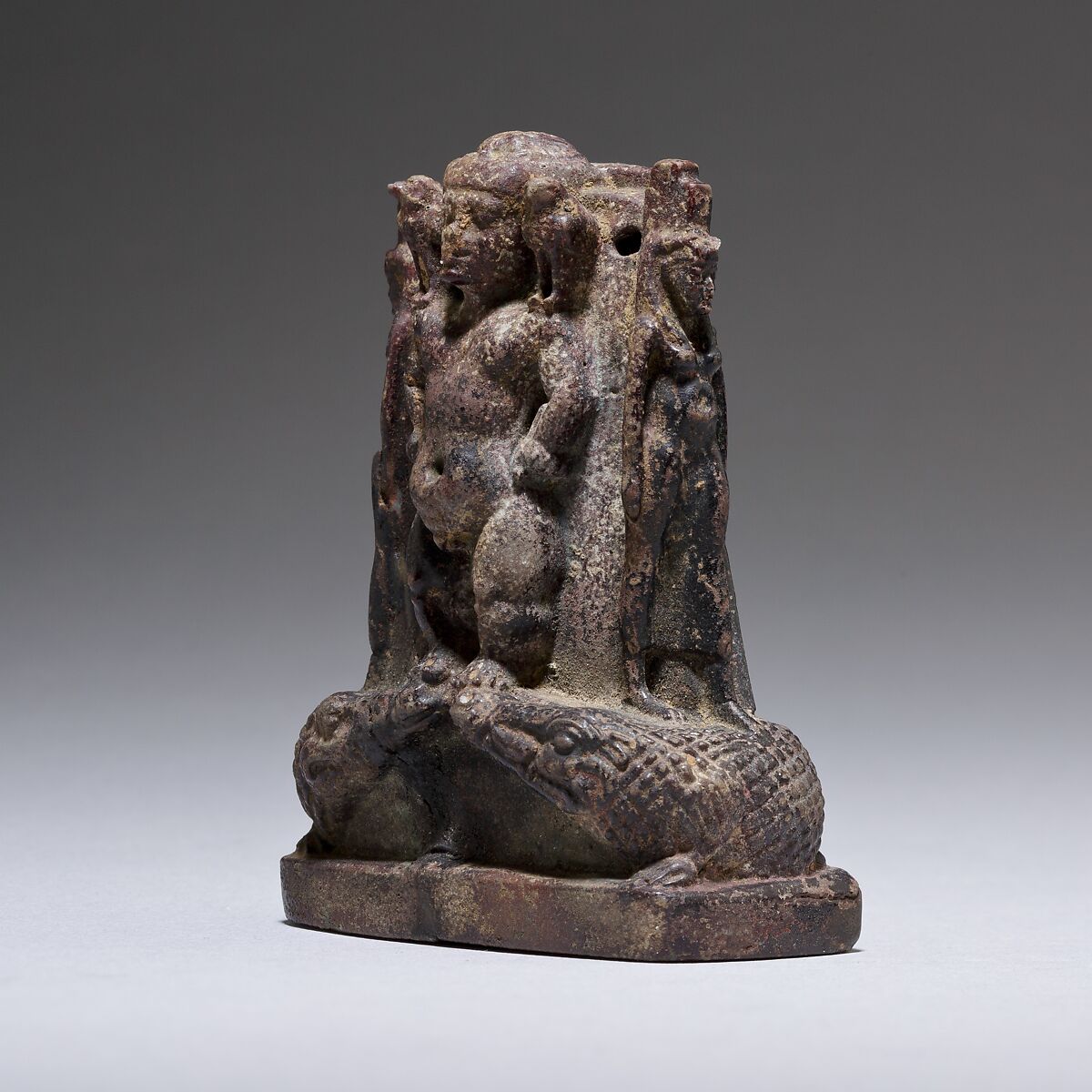 Cippus (magical stela) where Pataikos replaces Horus on the crocodiles and is flanked by Isis and Nephthys, Faience