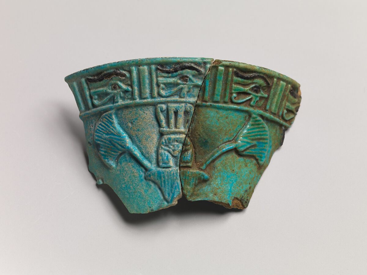 Relief chalice rim fragment with a wedjat frieze and below that a Hathor sistrum head emerging from papyrus plants, Faience 
