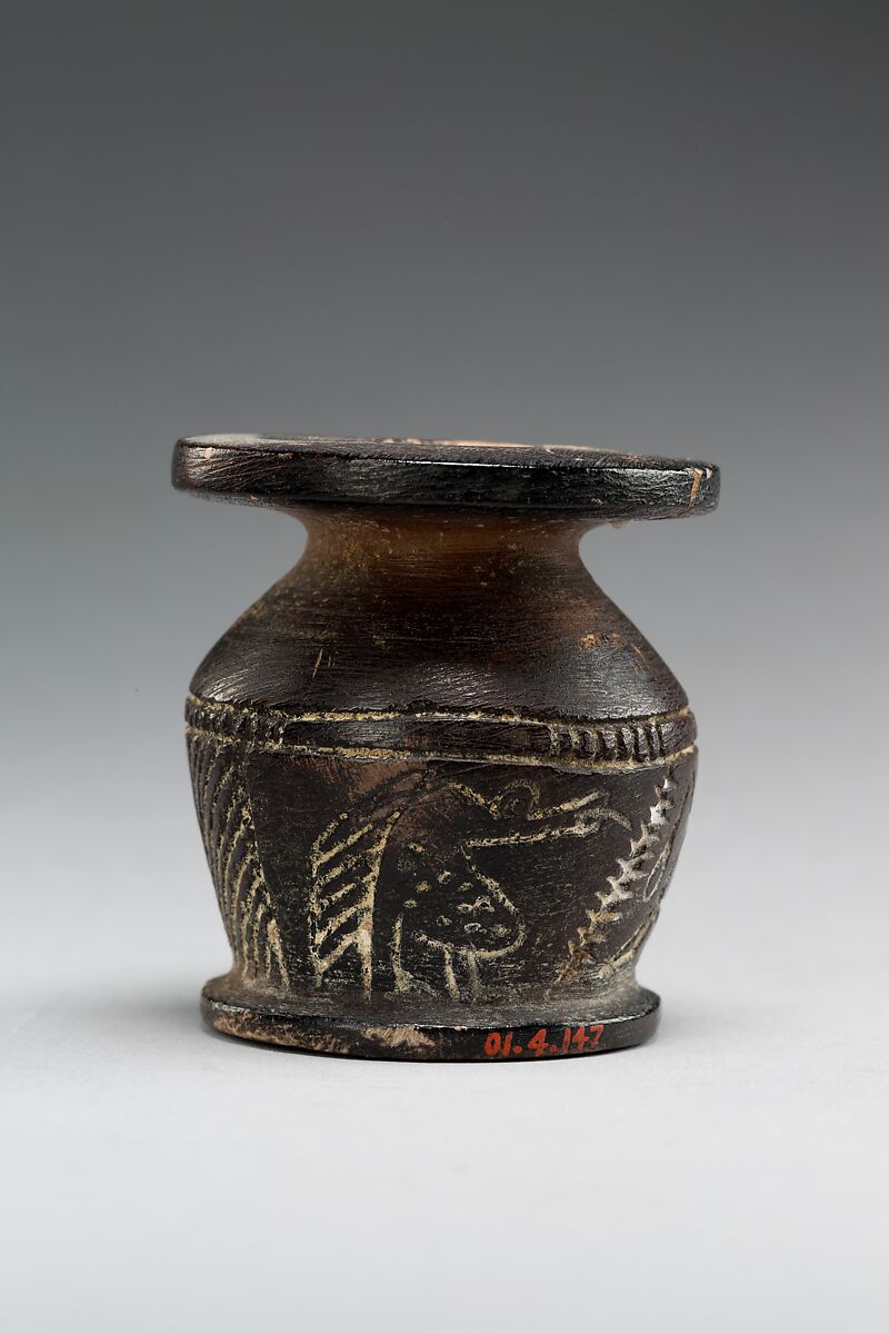 Kohl jar decorated wtih Horus falcon and grotesque figure, Blackened limestone