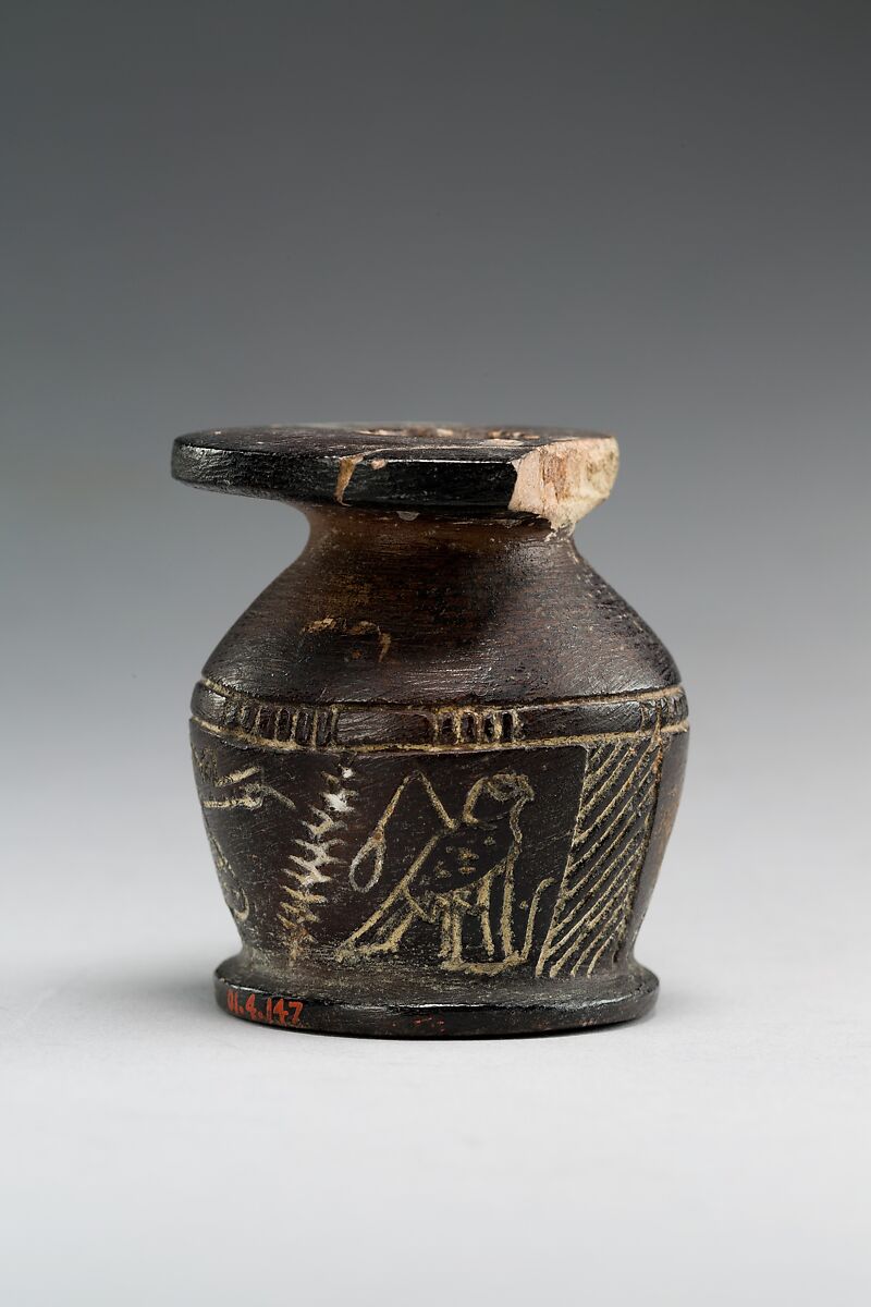 Kohl jar decorated wtih Horus falcon and grotesque figure, Blackened limestone