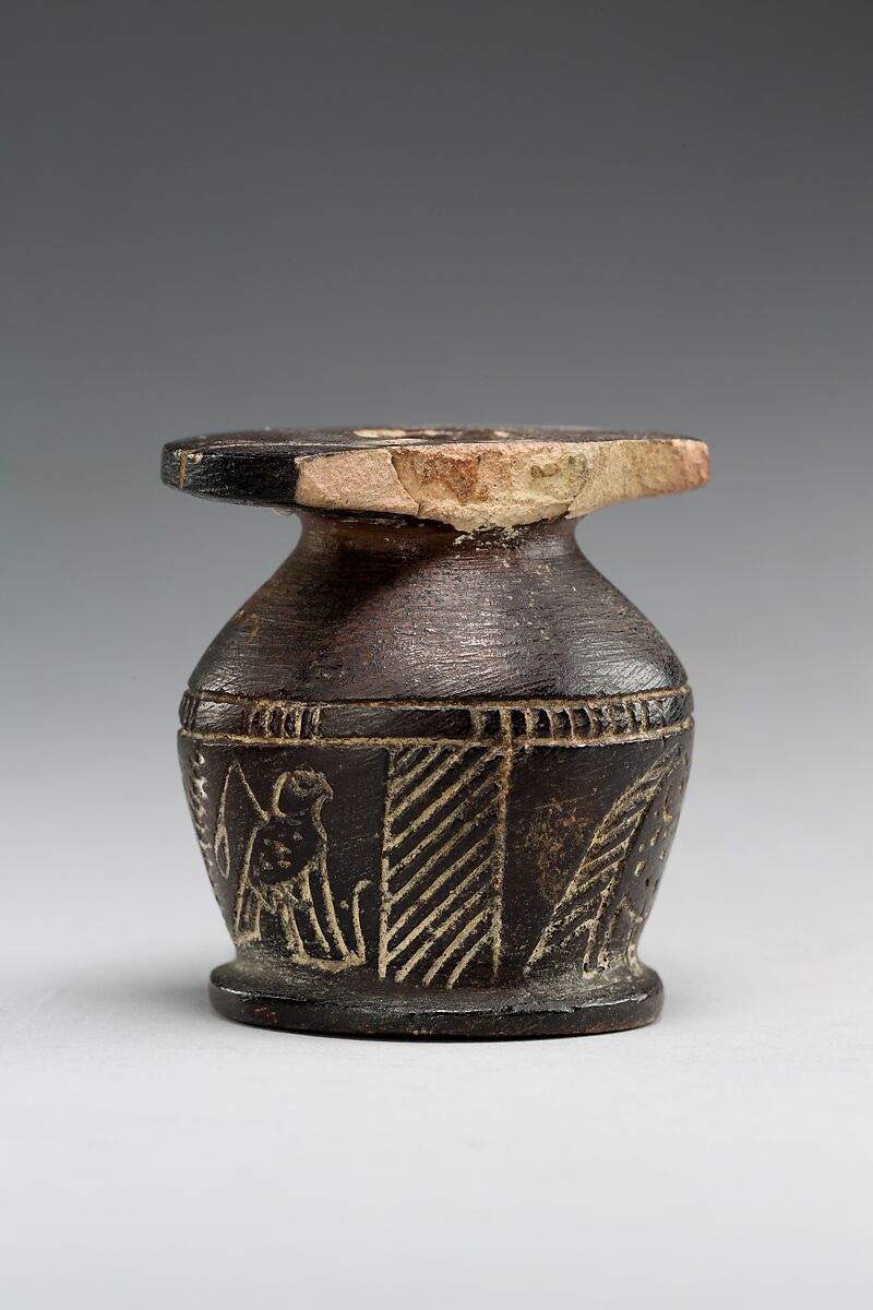 Kohl jar decorated wtih Horus falcon and grotesque figure, Blackened limestone