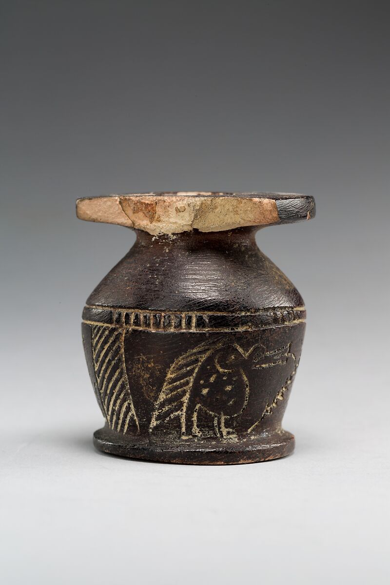 Kohl jar decorated wtih Horus falcon and grotesque figure, Blackened limestone