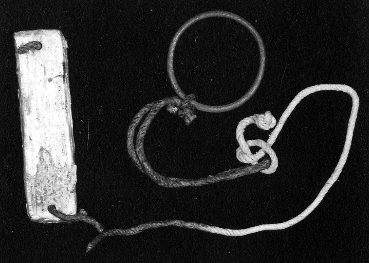 A plaque tied to a bracelet or ring with a cord, Metal, string 