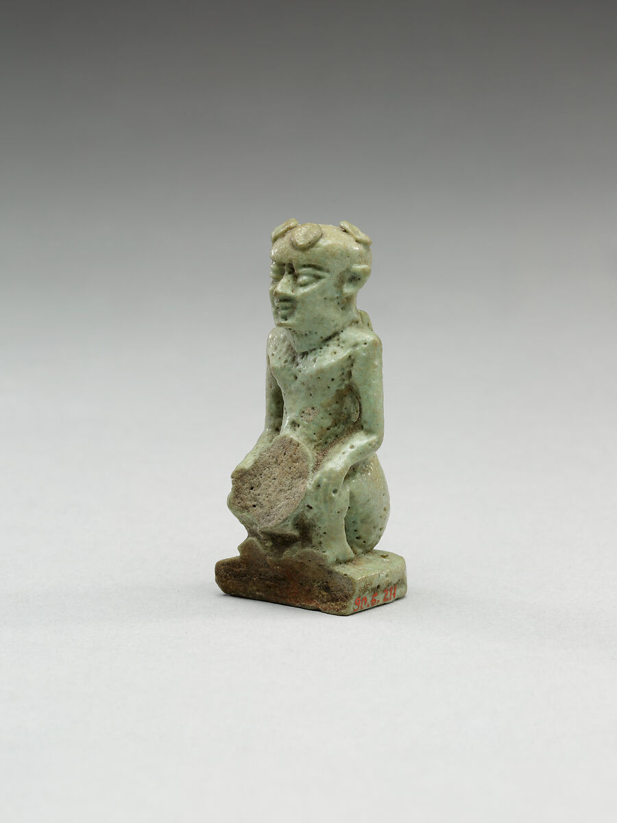 Nude crouching figure wearing a wreath, large phallus broken away, Faience 