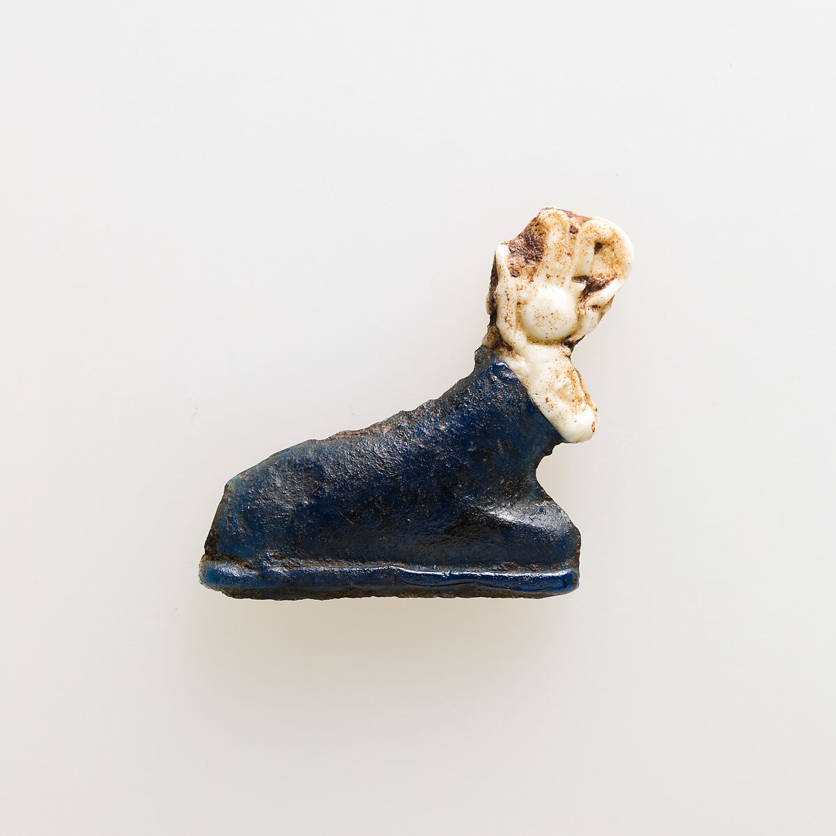 Amulet of kneeling cow wearing disk and feathers, Glass 