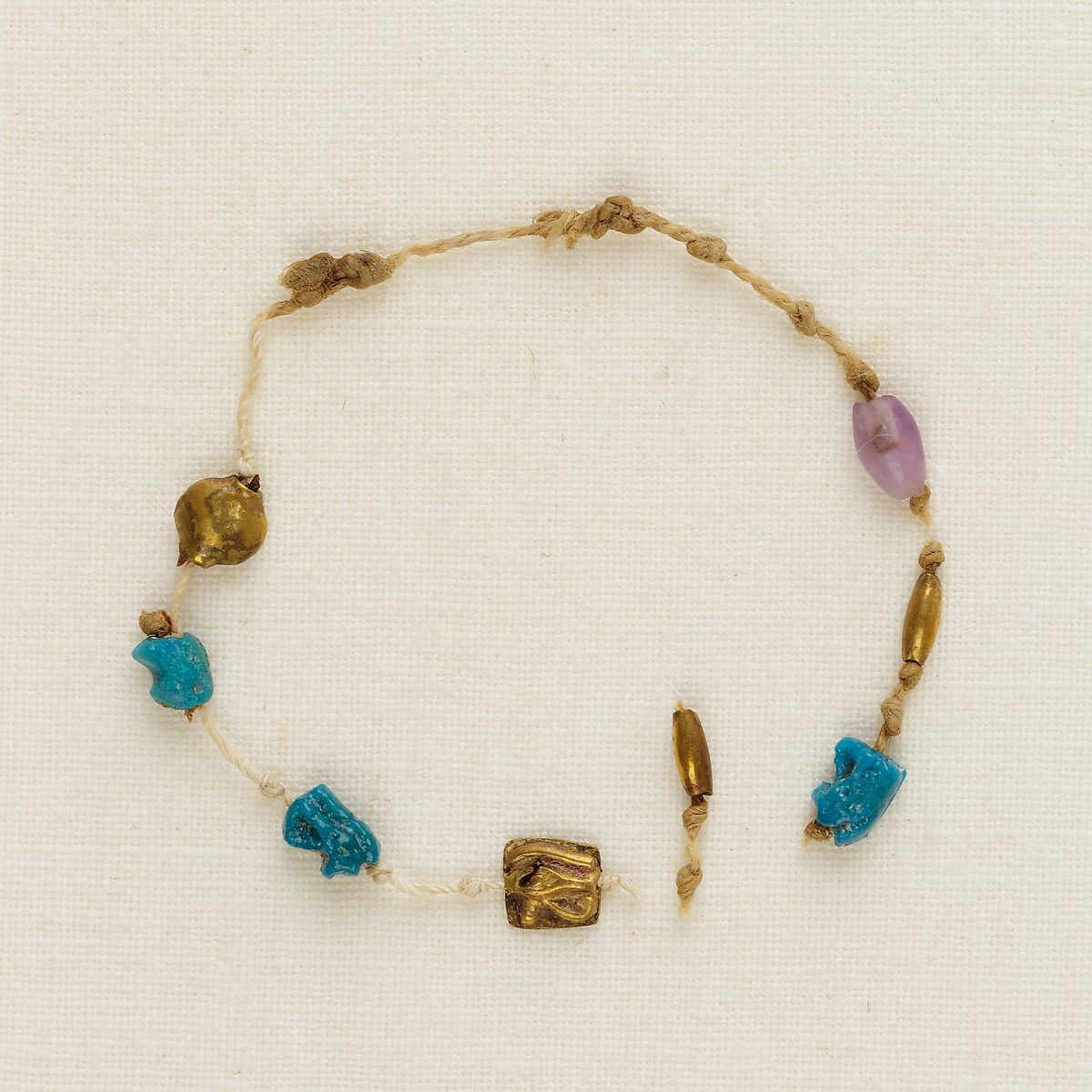 Bracelet with 4 wedjat eyes, 2 barrel beads, and 1 acacia bead, Linen, faience, gold, amethyst 