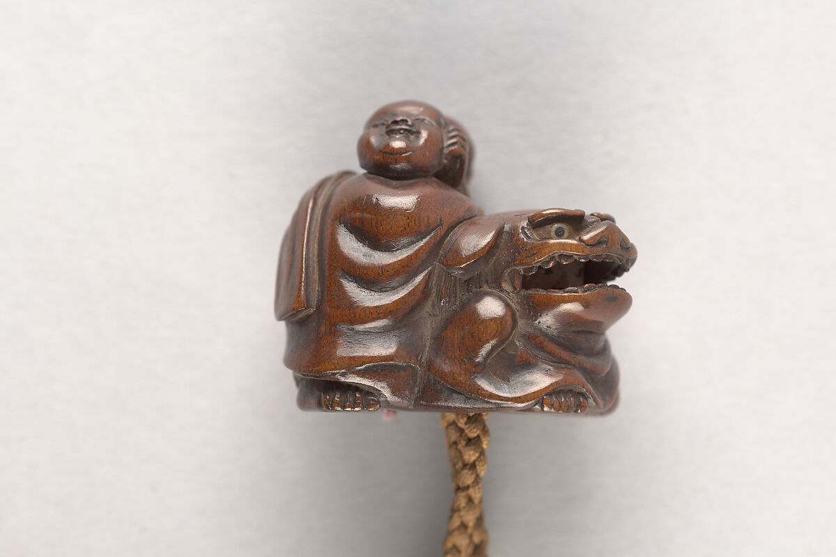 Inrō in the Shape of a Leather Tobacco Case (Tabakoire) with Flowering Plum, Attributed to Matsuda Sukenaga (Japanese, 1800–1871), Inrō: carved wood with lacquer imitating leather; gilded metal clasp; ojime: patinated metal bead; netsuke: Chinese boy (karako) with mask on shishi lion; carved wood, Japan