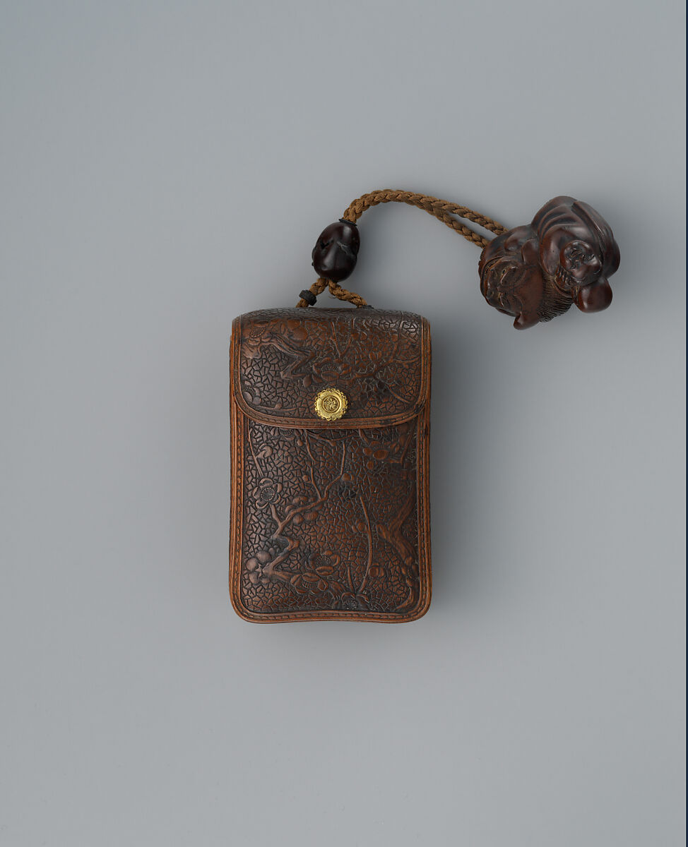 Inrō in the Shape of a Leather Tobacco Case (Tabakoire) with Flowering Plum, Matsuda Sukenaga  Japanese, Inrō: carved wood with lacquer imitating leather; gilded metal clasp; ojime: patinated metal bead; netsuke: Chinese boy (karako) with mask on shishi lion; carved wood, Japan