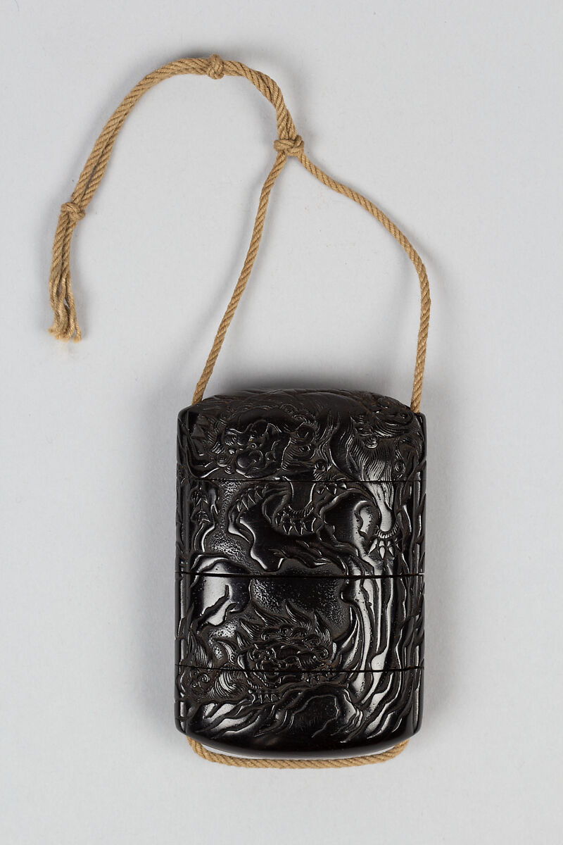 Case (Inrō) with Design of Shishi Dog Jumping and Climbing among Rocks and Bamboo, Wood, ebony, carved relief; Interior: plain & silver metal lining, Japan