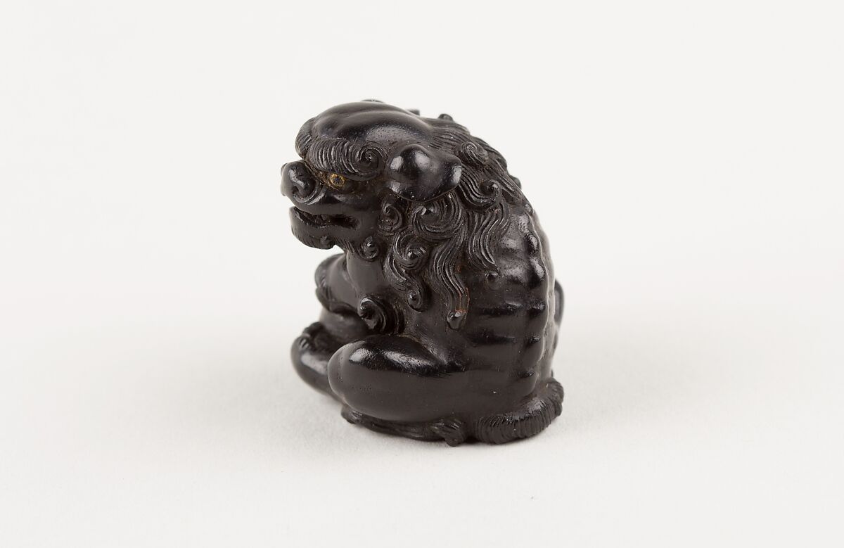Netsuke of Seated Shishi Clutching a Ball, Ryōzan (Japanese), Ebony with gold and horn inlay, Japan