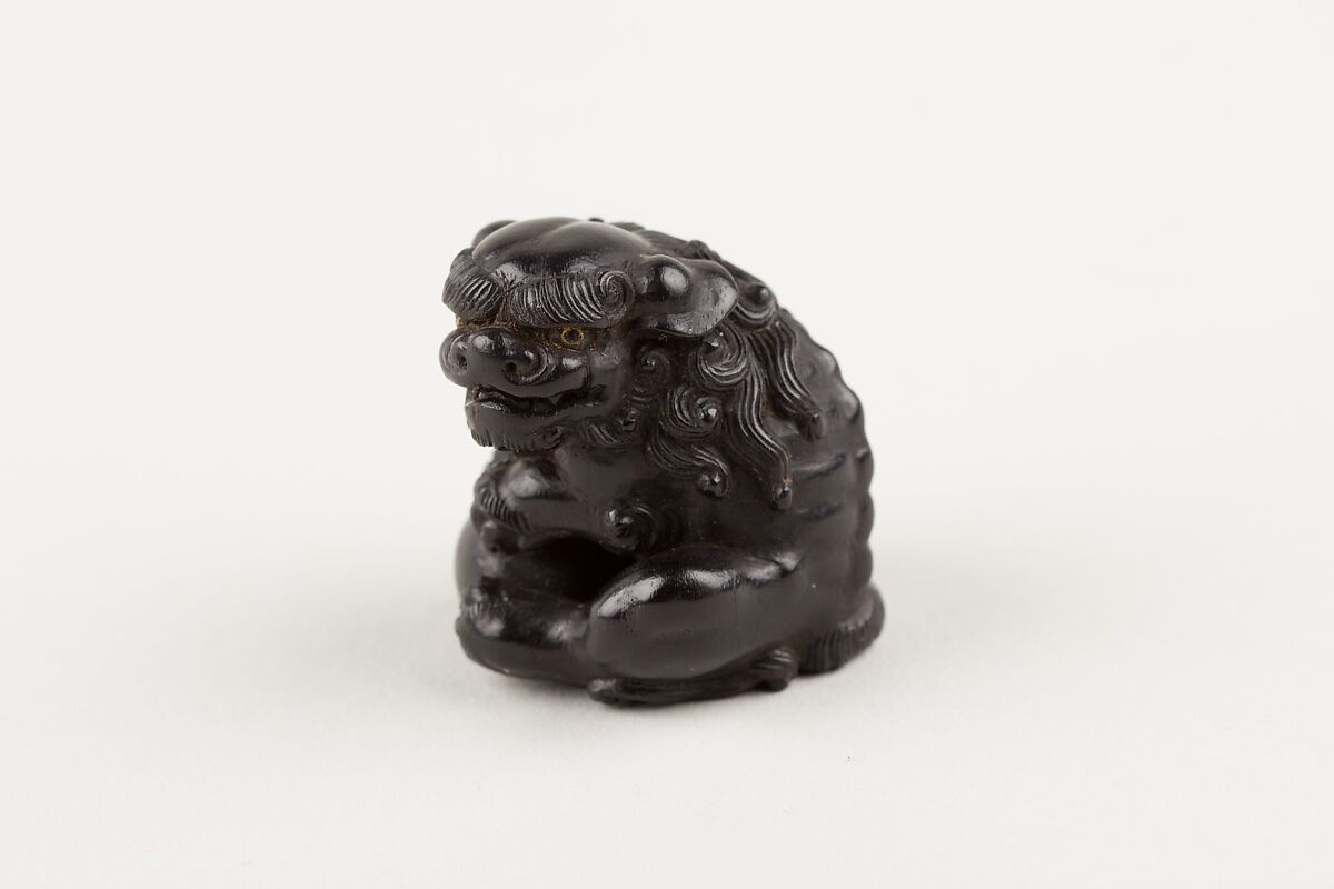 Netsuke of Seated Shishi Clutching a Ball, Ryōzan (Japanese), Ebony with gold and horn inlay, Japan