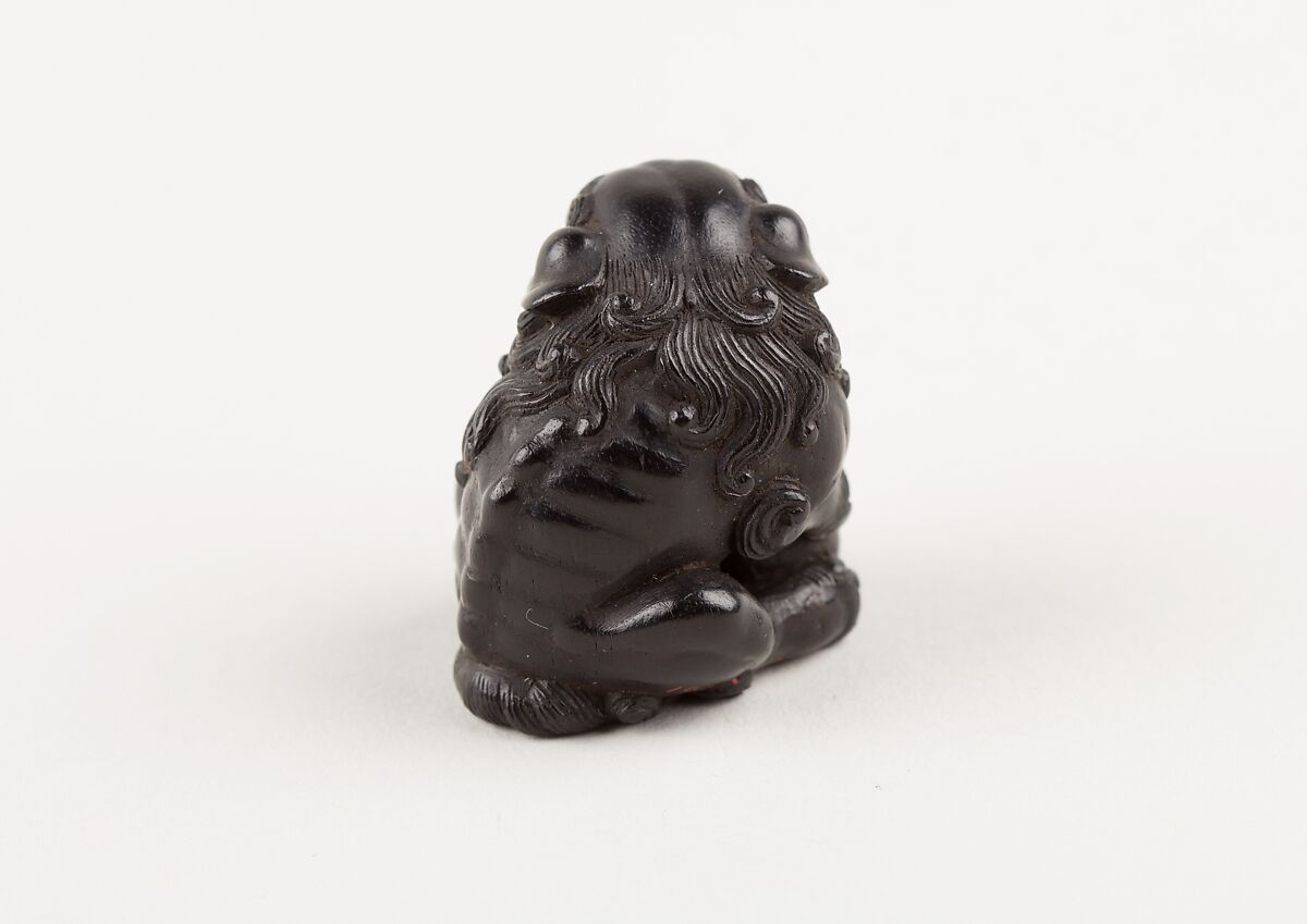 Netsuke of Seated Shishi Clutching a Ball, Ryōzan (Japanese), Ebony with gold and horn inlay, Japan