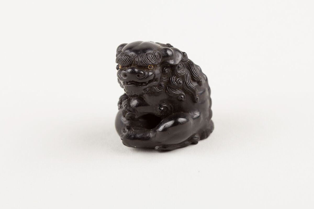 Netsuke of Seated Shishi Clutching a Ball, Ryōzan (Japanese), Ebony with gold and horn inlay, Japan