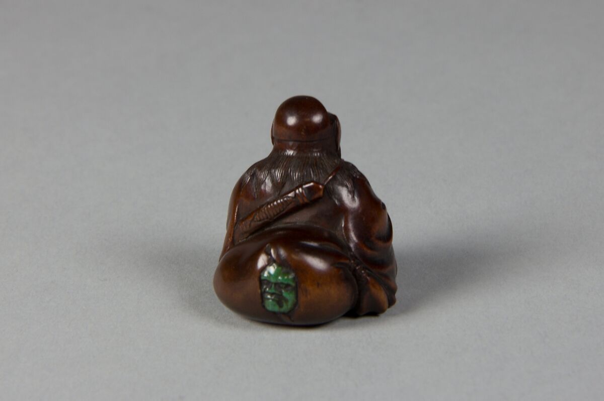 Netsuke of Seated Figure of an Old Man with Backpack Containing a Mask, Wood, Japan