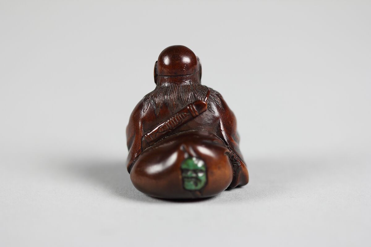 Netsuke of Seated Figure of an Old Man with Backpack Containing a Mask, Wood, Japan