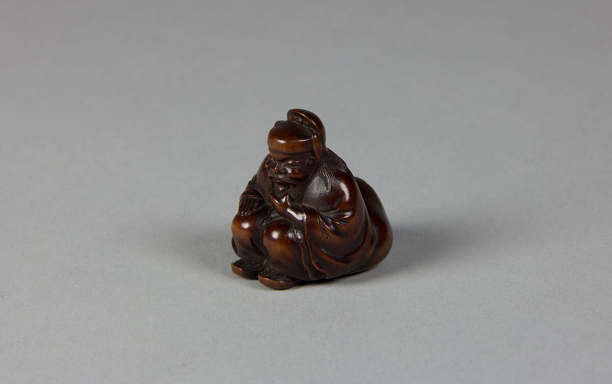 Netsuke of Seated Figure of an Old Man with Backpack Containing a Mask, Wood, Japan