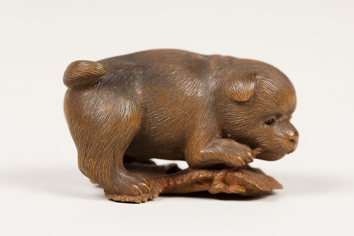 Netsuke of Puppy on Straw Mat Biting String, Wood, black pearls, Japan