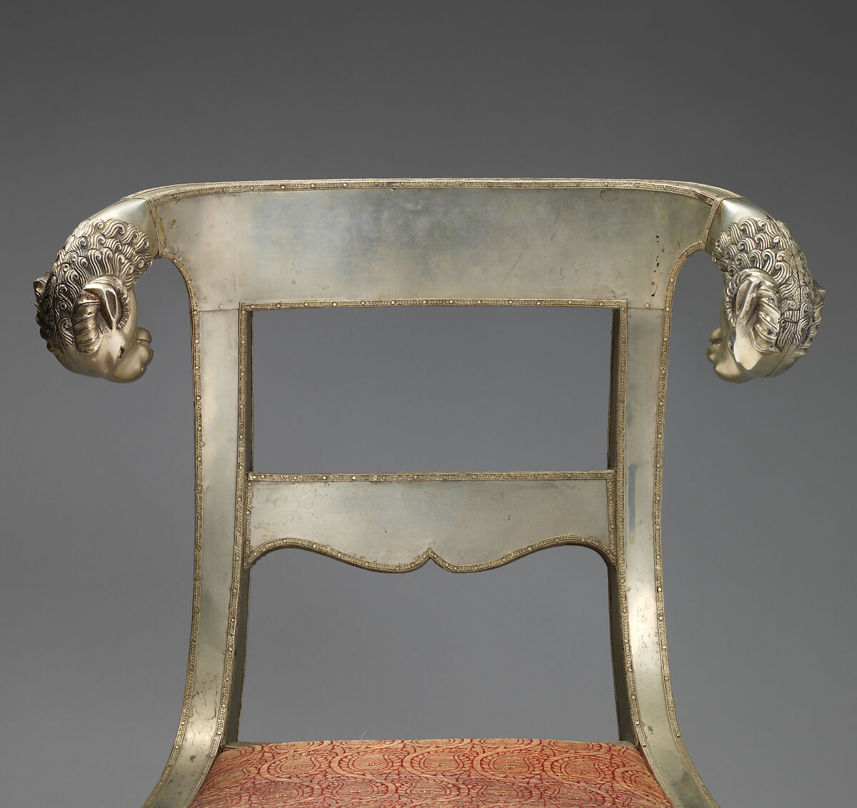 Side chair with rams' heads (one of a pair), White alloy metal sheets (silvered?) over wooden core, probaly teak; silk and metallic woven textile, Anglo-Indian