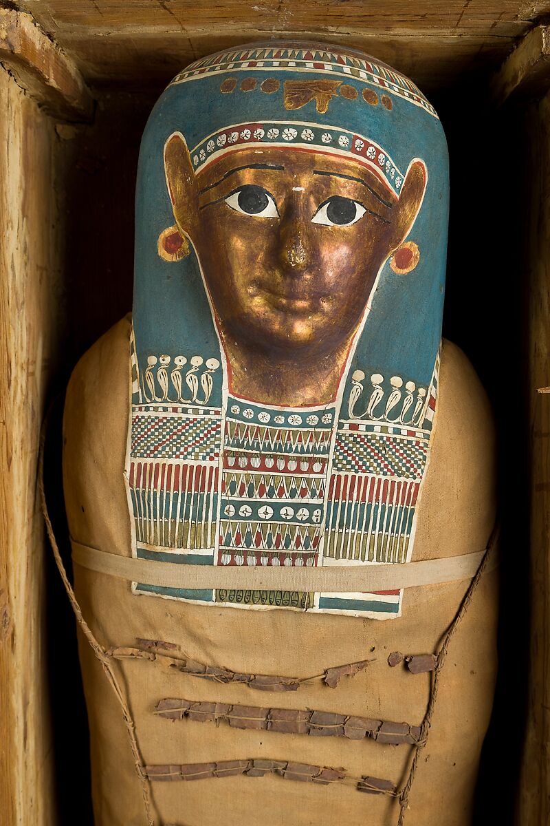 Mummy of Tasheriteniset with mummy mask and other cartonnage elements, also with garland of plants, Mummified human body, linen, mummification material, painted and gilded cartonnage, plant remains
