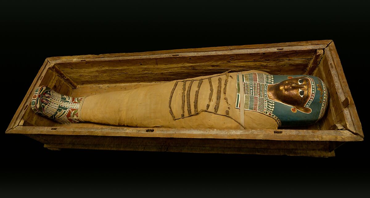Mummy of Tasheriteniset with mummy mask and other cartonnage elements, also with garland of plants, Mummified human body, linen, mummification material, painted and gilded cartonnage, plant remains