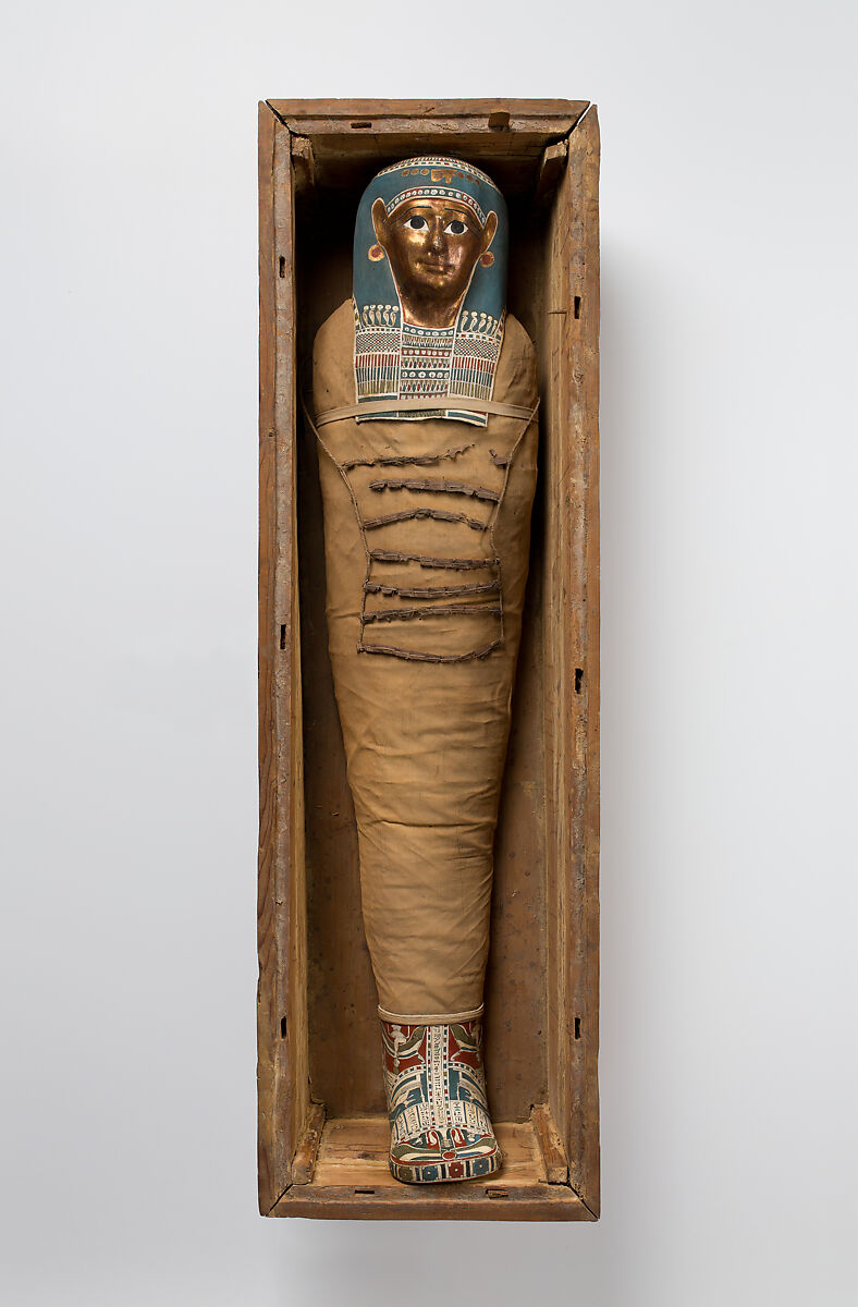 Mummy of Tasheriteniset with mummy mask and other cartonnage elements, also with garland of plants, Mummified human body, linen, mummification material, painted and gilded cartonnage, plant remains