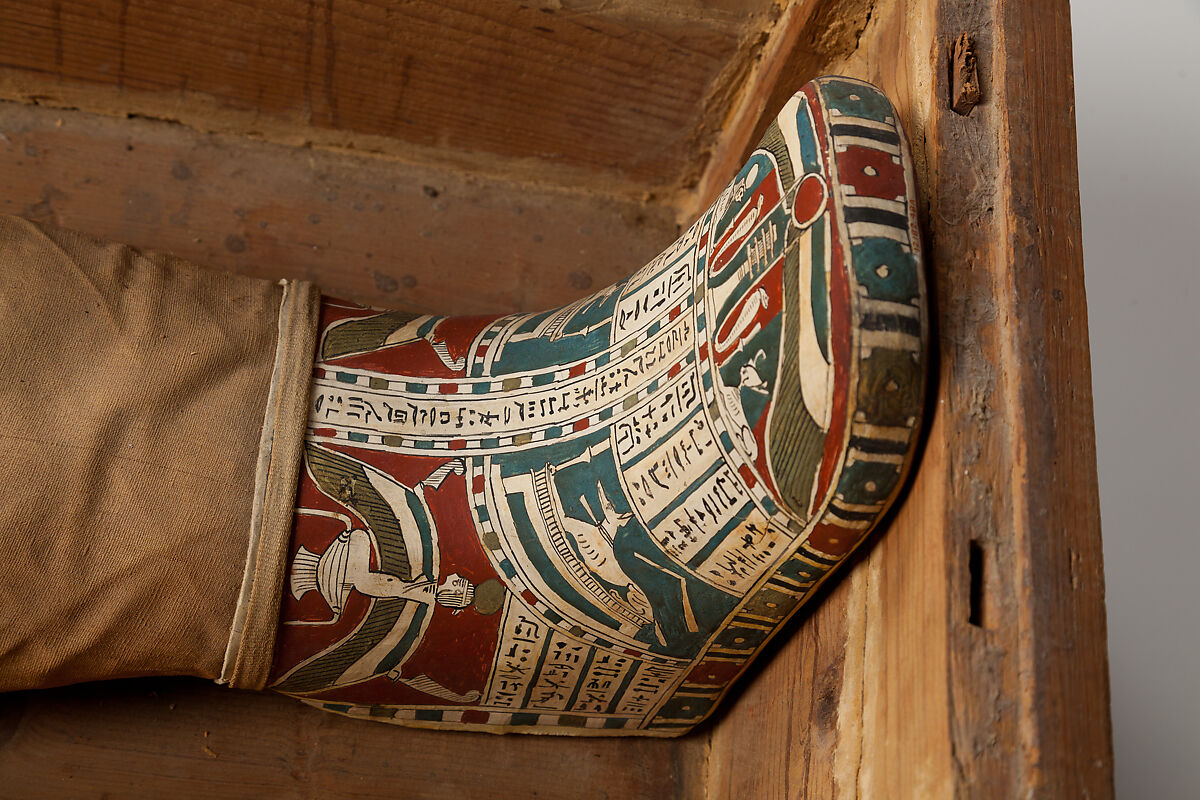 Mummy of Tasheriteniset with mummy mask and other cartonnage elements, also with garland of plants, Mummified human body, linen, mummification material, painted and gilded cartonnage, plant remains