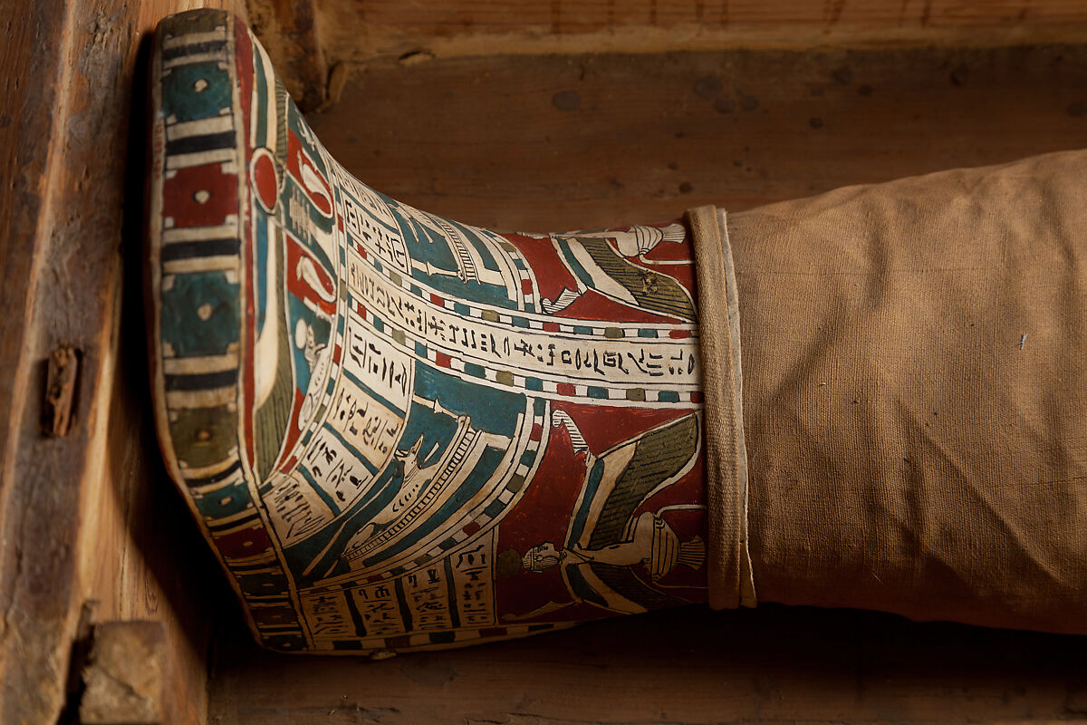 Mummy of Tasheriteniset with mummy mask and other cartonnage elements, also with garland of plants, Mummified human body, linen, mummification material, painted and gilded cartonnage, plant remains