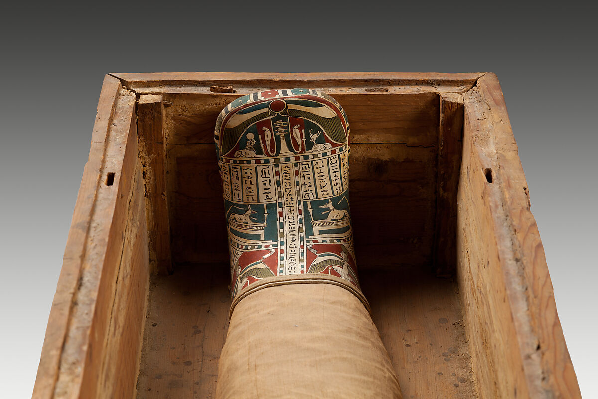 Mummy of Tasheriteniset with mummy mask and other cartonnage elements, also with garland of plants, Mummified human body, linen, mummification material, painted and gilded cartonnage, plant remains