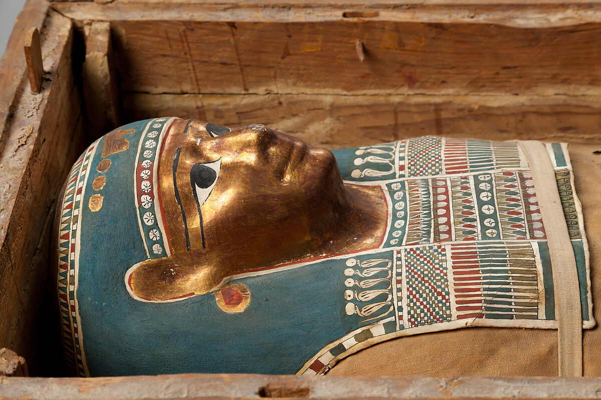 Mummy of Tasheriteniset with mummy mask and other cartonnage elements, also with garland of plants, Mummified human body, linen, mummification material, painted and gilded cartonnage, plant remains