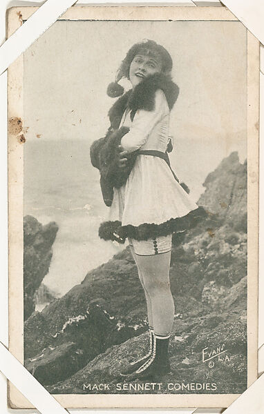 Bathing beauty in costume with fur standing on rocks from Mack Sennett Comedies Arcade series (W423), Commercial photolithograph 