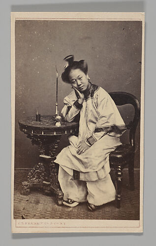 [Studio Portrait: Woman Seated Beside a Table Leaning on Elbow]