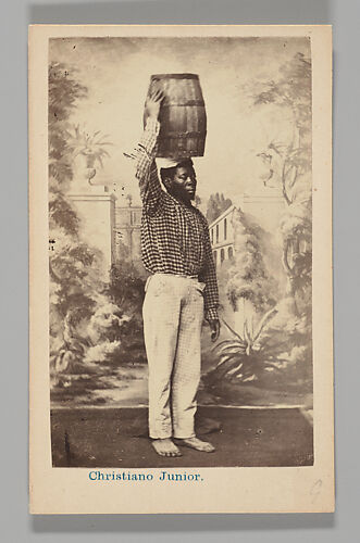 [Studio Portrait: Male Street Vendor with Barrel on Head, Brazil]