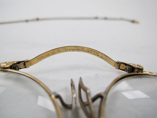 Eyeglasses, (a) gold, glass (b) metal, (c) leather , American
