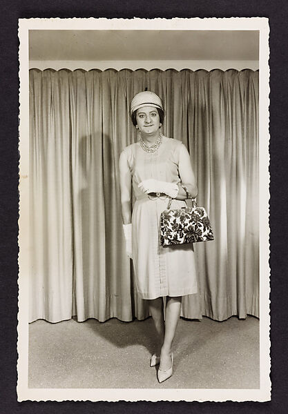 [Renée from Québec standing in front of a curtain with brocade handbag, location unknown]
, Unknown, Gelatin silver print